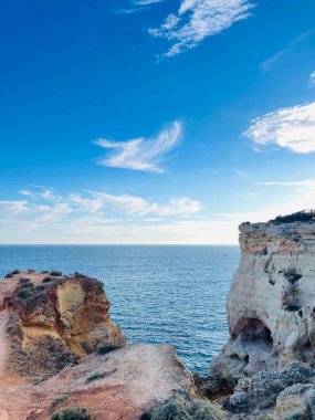 Fırtınalı bir denizden yükselen mağaraları olan yüksek kireçtaşı kayalıkları. Algar Seco, Carvoeiro Güney Portekiz, Algarve. Sahildeki kumtaşından resif oluşumu. Dikey fotoğraf. Boşluğu kopyala.