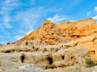Fırtınalı bir denizden yükselen mağaraları olan yüksek kireçtaşı kayalıkları. Algar Seco, Carvoeiro Güney Portekiz, Algarve. Sahildeki kumtaşından resif oluşumu. Yatay fotoğraf. Boşluğu kopyala