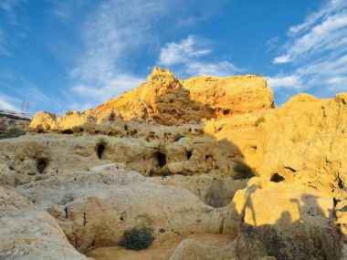 Fırtınalı bir denizden yükselen mağaraları olan yüksek kireçtaşı kayalıkları. Algar Seco, Carvoeiro Güney Portekiz, Algarve. Sahildeki kumtaşından resif oluşumu. Yatay fotoğraf. 