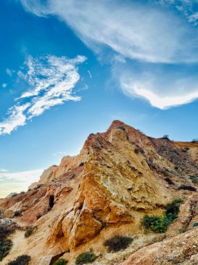 Fırtınalı bir denizden yükselen mağaraları olan yüksek kireçtaşı kayalıkları. Algar Seco, Carvoeiro Güney Portekiz, Algarve. Sahildeki kumtaşından resif oluşumu. Dikey fotoğraf. Boşluğu kopyala.