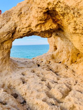 Fırtınalı bir denizden yükselen mağaraları olan yüksek kireçtaşı kayalıkları. Algar Seco, Carvoeiro Güney Portekiz, Algarve. Sahildeki kumtaşından resif oluşumu. Dikey fotoğraf. Boşluğu kopyala.