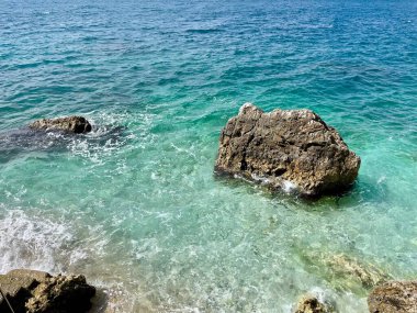 Arnavutluk 'taki Rocky plajı ve İyon Denizi' nin kristal turkuaz suyu. Çiçeklerle sakin ve rahatlatıcı bir manzara. Yaz tatili konsepti. Uzayı kopyala Yatay fotoğraf. 