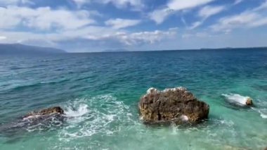 Arnavutluk 'taki Rocky plajı ve İyon Denizi' nin kristal turkuaz suyu. Çiçeklerle sakin ve rahatlatıcı bir manzara. Yaz tatili konsepti. Uzayı kopyala Yatay Yüksek Kaliteli FullHD görüntüleri