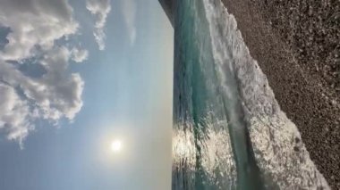 Arnavutluk 'taki Rocky plajı ve İyon Denizi' nin kristal turkuaz suyu. Çiçeklerle sakin ve rahatlatıcı bir manzara. Yaz tatili konsepti. Uzayı kopyala dikey video. Yüksek kaliteli FullHD görüntüler, 4k video