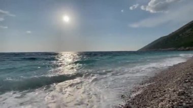 Arnavutluk 'taki Rocky plajı ve İyon Denizi' nin kristal turkuaz suyu. Çiçeklerle sakin ve rahatlatıcı bir manzara. Yaz tatili konsepti. Uzayı kopyala Yatay video. Yüksek kaliteli FullHD görüntüler, 4k video