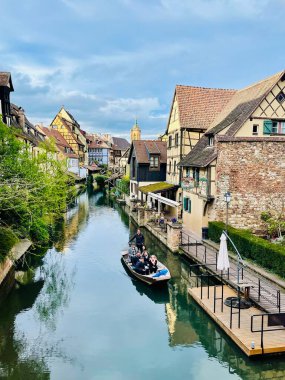 Colmar, Fransa - 01 Nisan 2024: Little Venice la Petite Venedik kanalında turistli tekne. Alsace kentsel ortaçağ manzarası, su kanalı ve geleneksel yarı keresteli evler, Colmar, Fransa