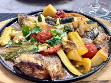 Taze sebzeli balık güvecini yakın ve siyah bir tabakta servis edin. Sağlıklı gıda konsepti. 