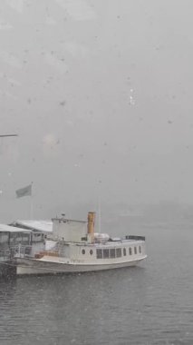 Stockholm, İsveç, güzel apartmanlar ve gri günde turist tekneleri. Gerçek zamanlı video. 4K, Dikey, kar zamanı 