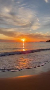 Gün batımında kumlu sahilde dalgaların gökyüzüne doğru aktığı manzara. Yüksek kaliteli FullHD görüntüler. 4K video. Korfu, Yunanistan 'daki Ada. 