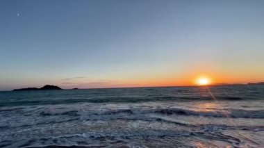 Gün batımında kumlu sahilde dalgaların gökyüzüne doğru aktığı manzara. Yüksek kaliteli FullHD görüntüler. 4K video. Korfu, Yunanistan 'daki Ada. 