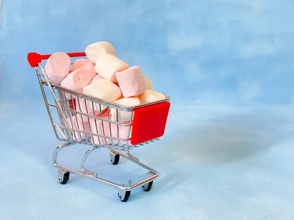 Marshmallow 'lu bir süpermarketten minyatür sepet. Mavi arka plan. - Uzayı kopyala