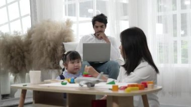 Orta Doğulu baba evde bilgisayarla çalışırken Asyalı anne kızıyla atıştırmalık yiyor.