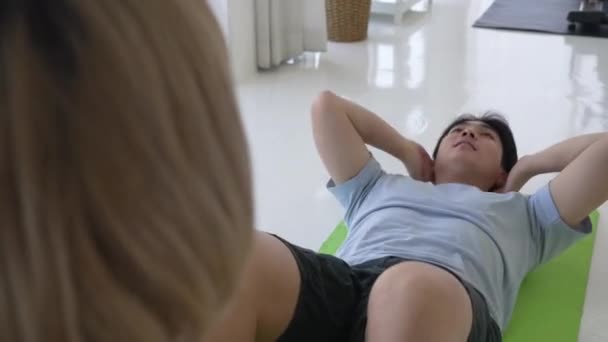 Jonge Aziatische Trainer Helpen Man Doen Sit Oefening Thuis — Stockvideo