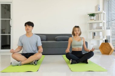 Genç Asyalı çift evde yoga yapıyor.