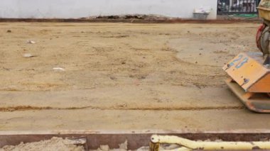 Kum sıkıştırmak için Plaka Sıkıştırıcı kullanan İşçi Görünümünü kapat. Asfalt Asfalt Asma Süreci