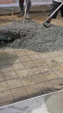 Kürek ve tırmıkla zemine beton döşeyen işçilerin dikey görüntüsü. İnşaat Konsepti