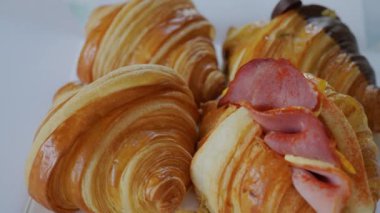 Sade, jambonlu ve peynirli çeşitli kruvasanların dönüşümlü görüntüsü