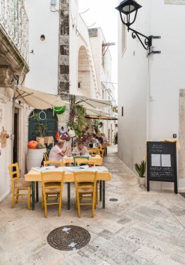 Locorotondo, Puglia, İtalya - 5 Ekim 2023: Bari ilindeki Locorotondo antik köyündeki açık hava restoranlarının tadını çıkaran turistler.