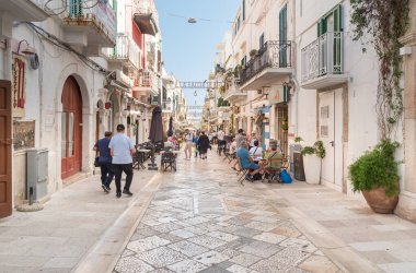Polignano a Mare, Puglia, İtalya - 4 Ekim 2023: Bari ilinin Polignano a Mare köyünde bar ve restoranları olan cadde.