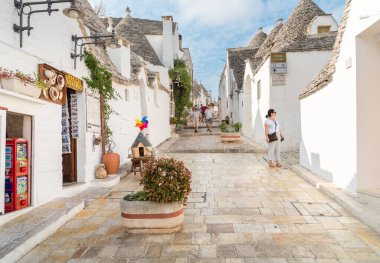 Alberobello, Puglia, İtalya - 5 Ekim 2023: Bari ilindeki Alberobello antik köyündeki trulli kireçtaşı evleri ziyaret eden turistler.