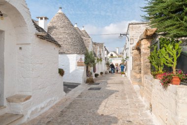 Alberobello, Puglia, İtalya - 5 Ekim 2023: Bari ilindeki Alberobello antik köyündeki trulli kireçtaşı evleri ziyaret eden turistler.
