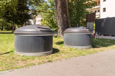 Modern kentsel atık yönetim sisteminin bir parçası olarak İsviçre 'nin Locarno şehrinde bir sokakta atık ayıklama için kullanılan iki büyük, yuvarlak gri çöp kutusu..