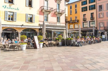 Lugano, Ticino, İsviçre - 19 Nisan 2018: İnsanlar Lugano 'nun tarihi merkezinde Piazza della Riforma' da bir açık hava barında rahatlıyor ve eğleniyorlar.