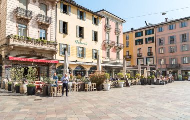 Lugano, Ticino, İsviçre - 19 Nisan 2018: İnsanlar Lugano 'nun tarihi merkezinde Piazza della Riforma' da bir açık hava barında rahatlıyor ve eğleniyorlar.