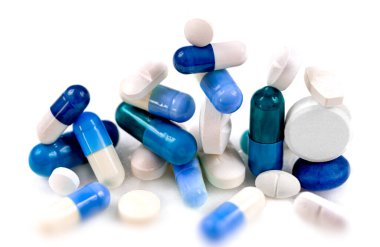 Blue and white capsules and tablets on a white background. clipart