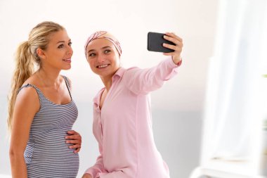 Hastanede iki genç kadın ziyaret sırasında selfie çekiyor.