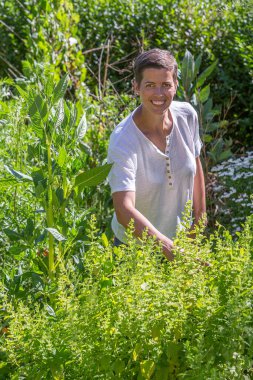 Tıbbi bitkilerin ortasında gülümseyen genç bir kadın.