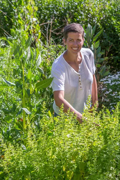 Tıbbi bitkilerin ortasında gülümseyen genç bir kadın.