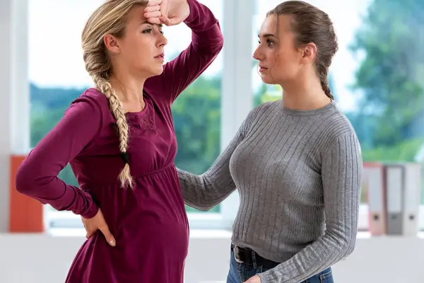 Молодая Беременная Женщина Чувствует Головокружение Поддержке Коллеги Стоковое Изображение