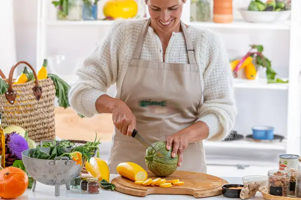 Junge Frau Ihrer Küche Umgeben Von Bio Gemüse lizenzfreie Stockbilder