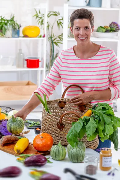 キッチンワークデスクに野菜を置く若い女性 ロイヤリティフリーのストック画像
