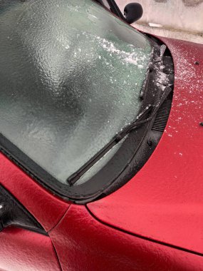 Arabasının donmuş camlarından buz kazıyarak..