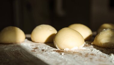 Ahşap tezgahta hamur topları ve un yakın plan. Pişirmeye hazır. Güneş ışığı.