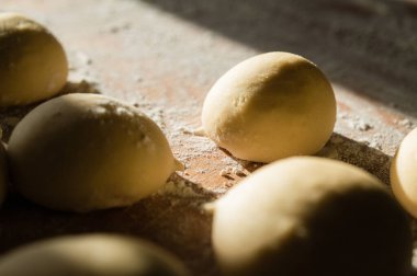Ahşap tezgahta hamur topları ve un yakın plan. Pişirmeye hazır. Güneş ışığı.