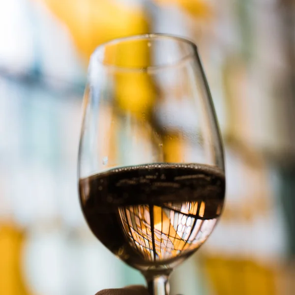透过玻璃杯中闪烁着白光的葡萄酒看一个色彩斑斓的玻璃窗 — 图库照片