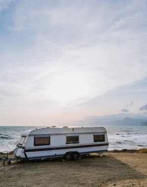 Karavan deniz kıyısına park etmiş. Suda dalgalar. Vahşi kamp yeri manzarası. Seyahat et. Tatil.
