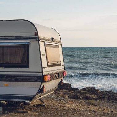 Karavan deniz kıyısına park etmiş. Suda dalgalar. Vahşi kamp yeri manzarası. Seyahat et. Tatil.