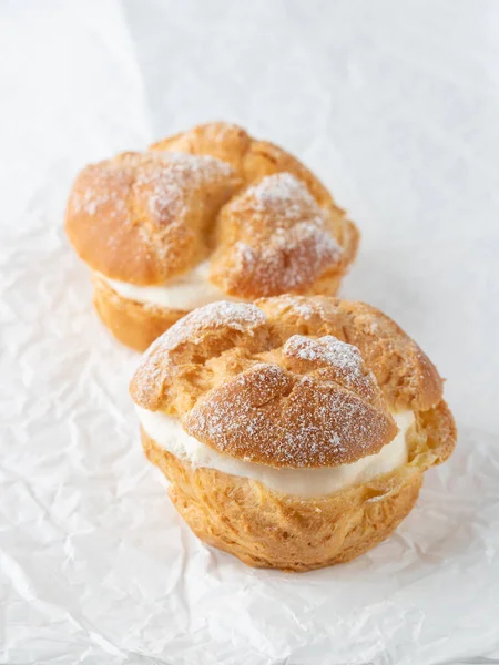 奶油泡芙 用乳酪包着糖粉的糕点涂在白纸上 喝咖啡休息或聚会的甜食 — 图库照片