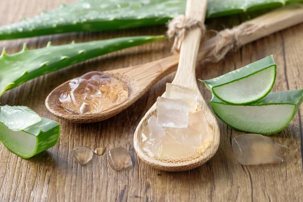 stock image Slices of medicinal pure aloe vera leaf with pulp ang gel on bamboo spoons on wooden background. Component of healthy food and natural skin care. Sliced aloe vera leaf closeup.