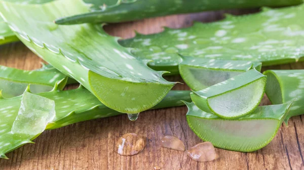 Ahşap tahtaya dilimlenmiş saf aloe vera yaprağından damlayan meyve suyu. Dilimlenmiş aloe vera yaprakları ve yakın plan jel damlaları. Sağlıklı gıda ve doğal cilt bakımı bileşeni.