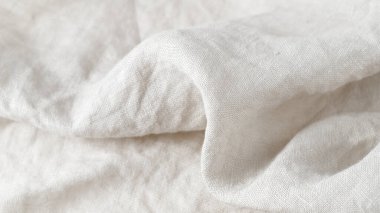 Arkaplanda fotokopi alanı olarak yumuşak beyaz renkli doğal keten kumaş. Saf keten kumaş.