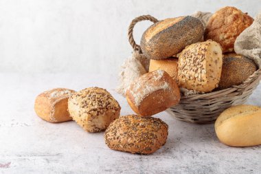 Arka plandaki grunge stone masasında taze çıtır ekmek çörekleri. Afyon, susam, keten ve ayçiçeği tohumlu çörekler kahvaltıda..