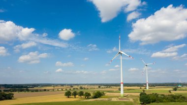 Rüzgâr türbinlerinin hava görüntüsü, yel değirmenlerinin tarlaları gökyüzüne karşı bulutlarla çevrili. Almanya 'da alternatif ekolojik enerji üretimi. İklim kavramını değiştir. Drone fotoğrafçılık, doğa manzarası