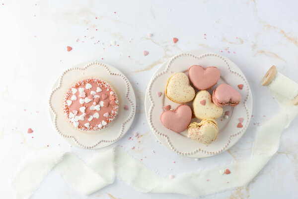 Французское сладкое печенье макарон с цветными брызгами на ретро пластины на мраморном фоне стола. Макароны в форме сердца, кексы и декор. Открытки-макеты с местом для копирования.