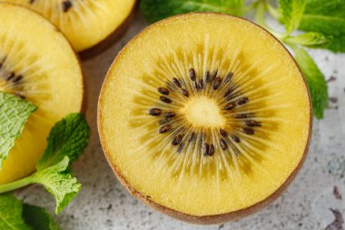 Olgun çiğ kivi altın dilimleri ve nane yaprakları grunge beyaz taş masa üzerinde yakın çekim. Kopyalama alanı olan üst görünüm