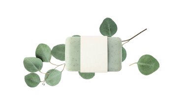 Boş kağıt kapaklı yeşil bitkisel sabun ve beyaz arka planda izole edilmiş taze okaliptüs dalları. Vücut bakımı el işi ürünü ya da spa sağlık konsepti. Kopyalama alanı olan maket kartı